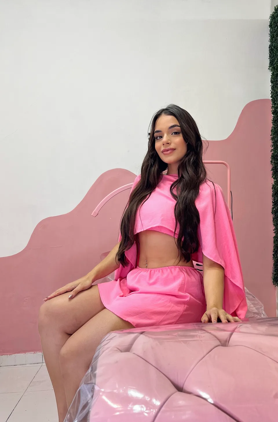 Giovana Pincela, vestindo rosa, sentada em seu estúdio